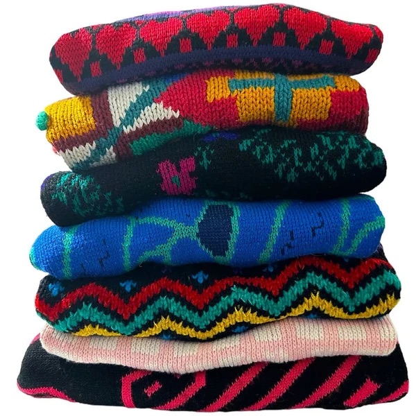 Stack of colorful patterned vintage women’s sweaters.